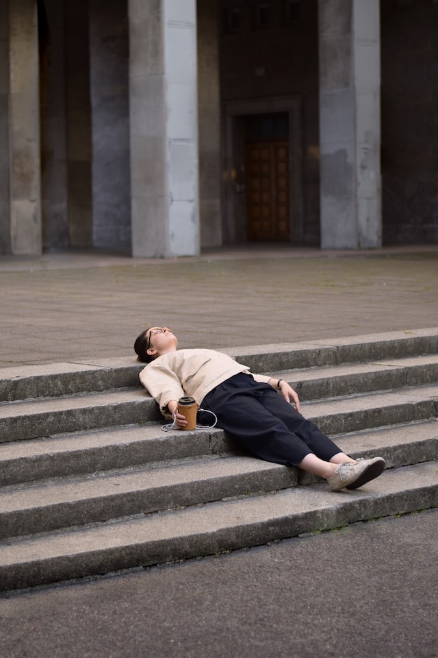 Woman lying on stairs holding a JOYUMA coffee carrier. Berlin, Germany.